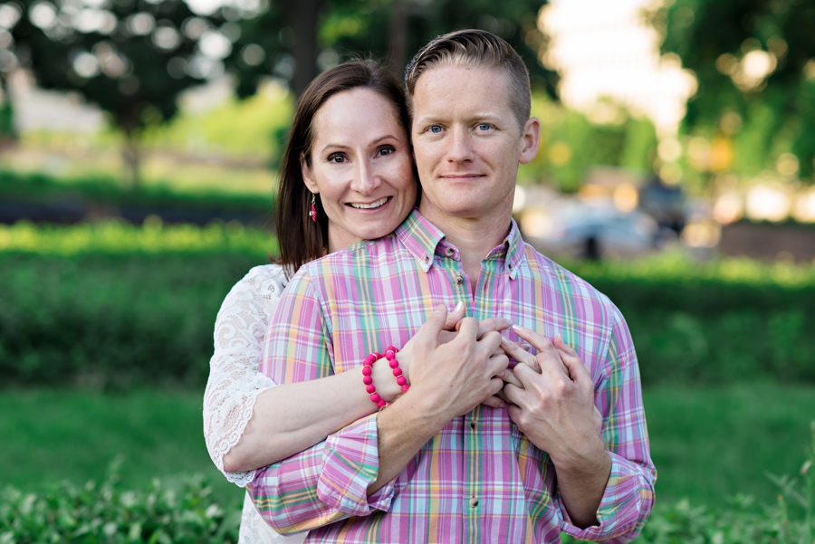 A woman hugs her fiance from behind as they laugh.